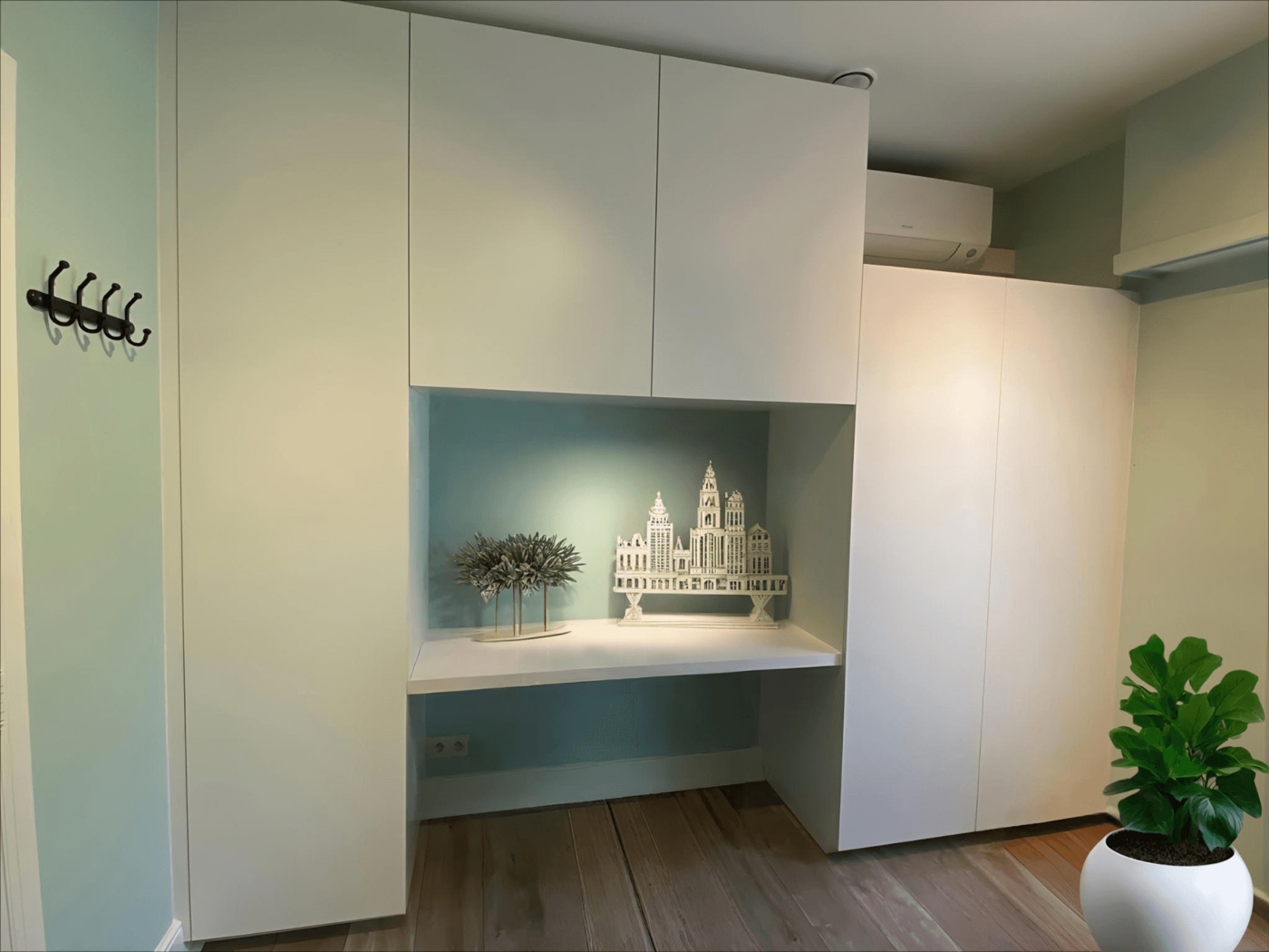 Witte kastenwand van vloer tot plafond met een verlichte nis en werkblad